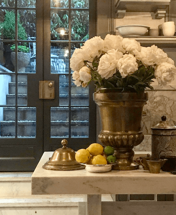 Steven Gambrel gorgeous vignette - peonies- brass urn-French doors- kitchen definitely not bland decor