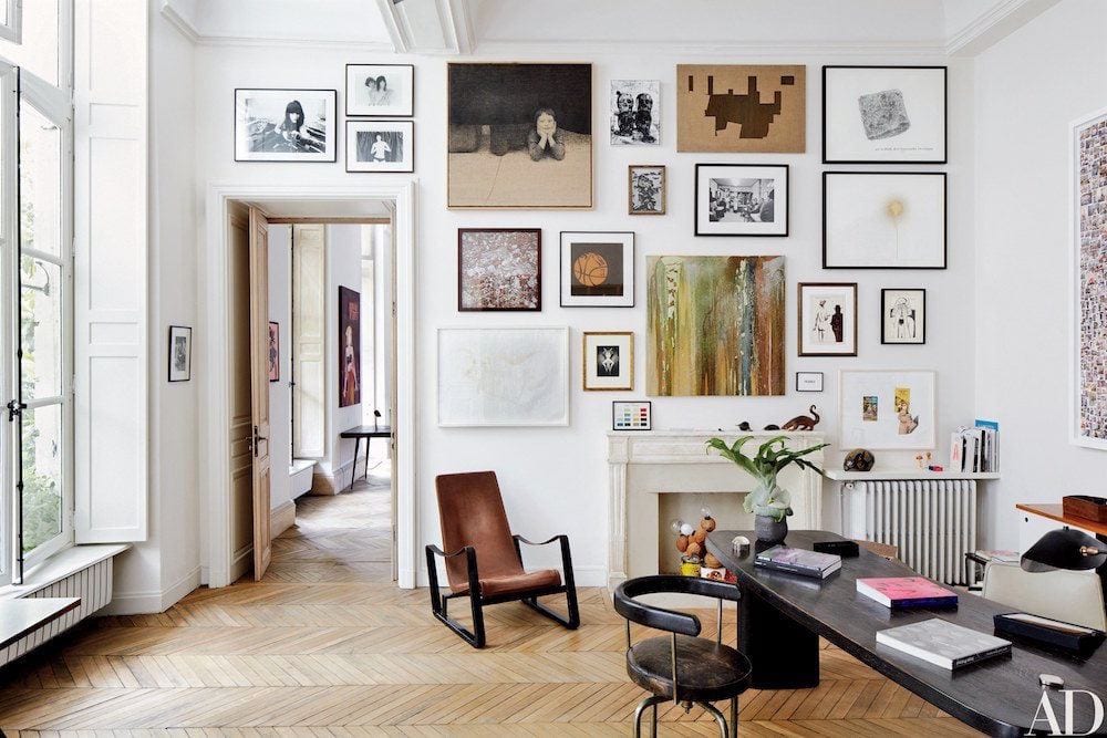 Paris apartment of design dealers Laurence and Patrick Seguin features a wall of artworks - via Architectural Digest - photo: Simon Watson